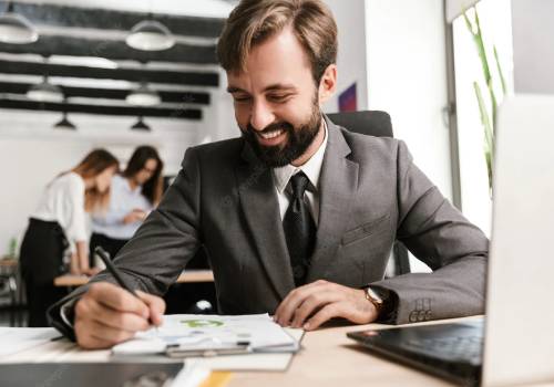 A man in a suit and tie writing on paper.