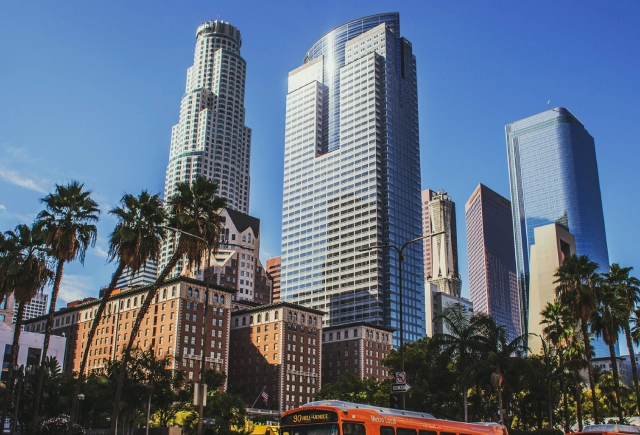 A bus driving down the street in front of tall buildings.