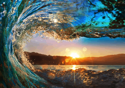 A wave is seen in the water as the sun sets.